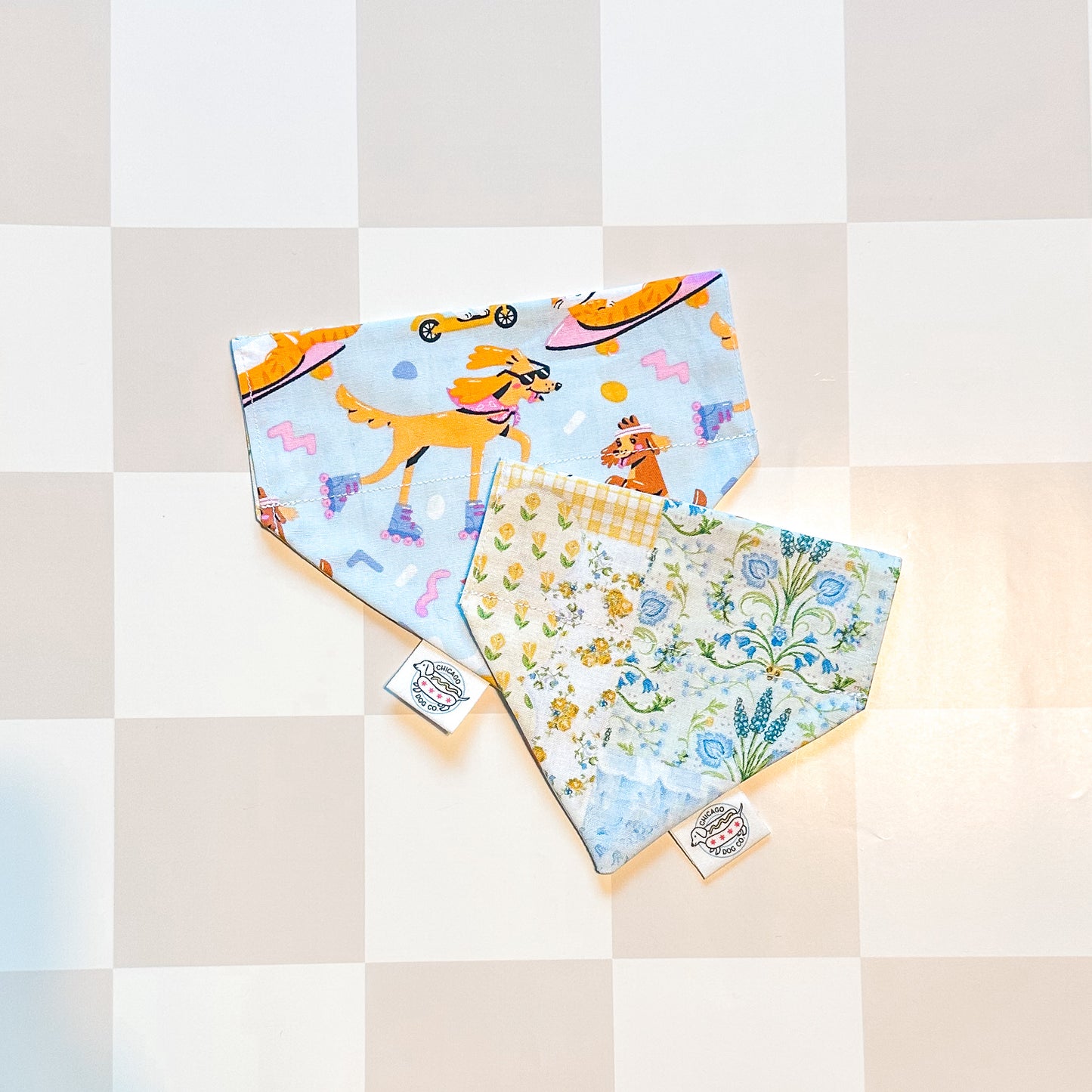 Two colorful bandanas with dog-themed designs on a checkered background