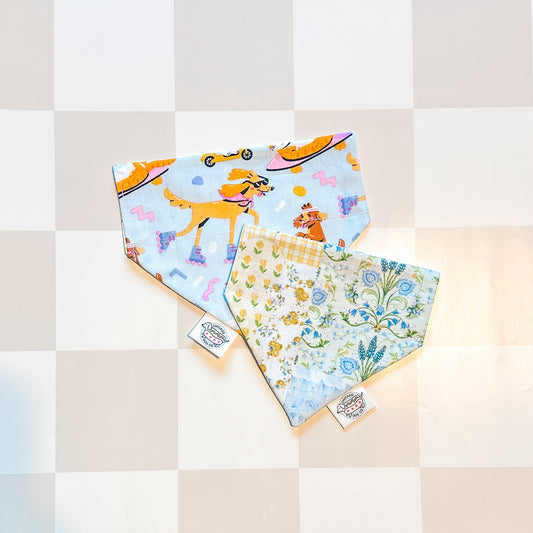 Two colorful bandanas with dog-themed designs on a checkered background