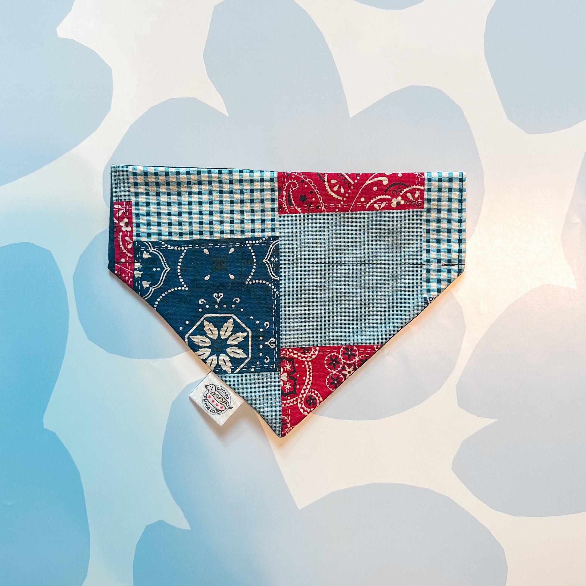 Patchwork red, white and blue 4th of July pet bandana with various patterns on a light blue background
